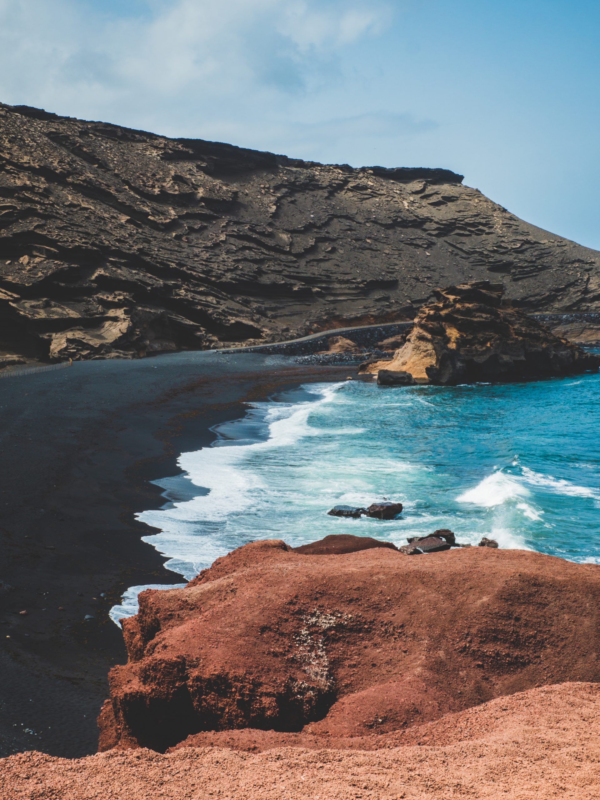Cette plage de sable noir dispose d'une eau turquoise.